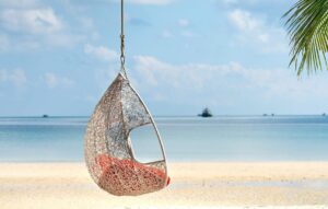 A peaceful scene with a hanging swing chair on a tropical beach, perfect for relaxation.